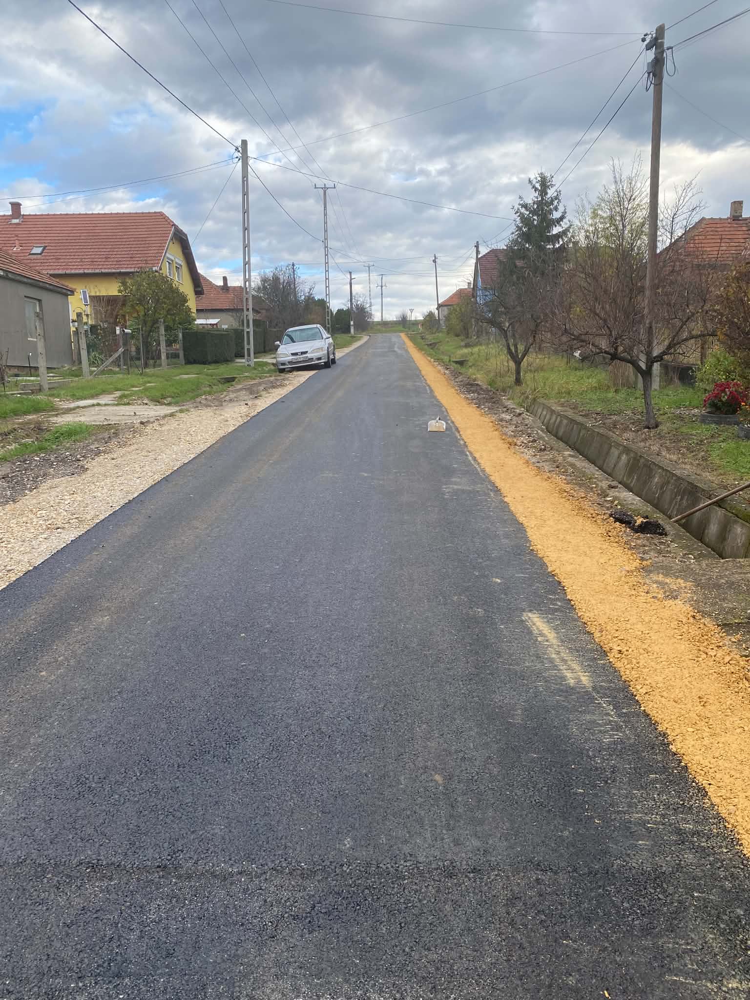 Frissen aszfaltozott út zúzottkő padkával